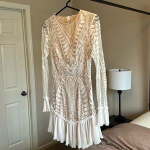 White, long sleeve lace dress with ruffle hem.